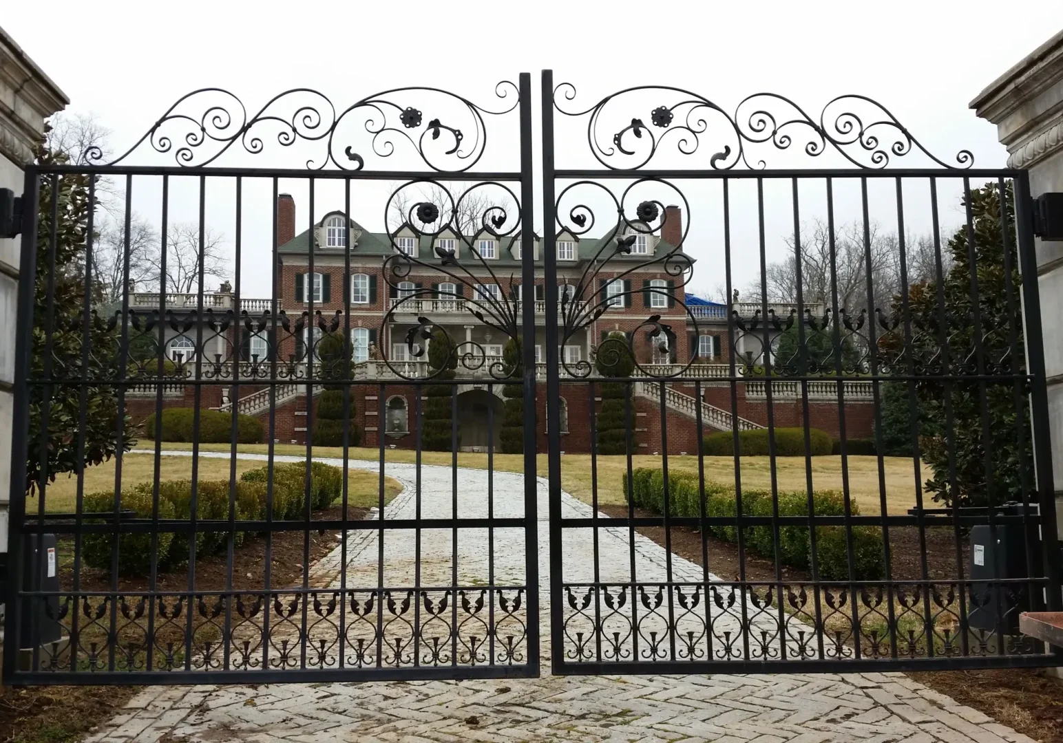 A gated driveway leading to an old mansion.
