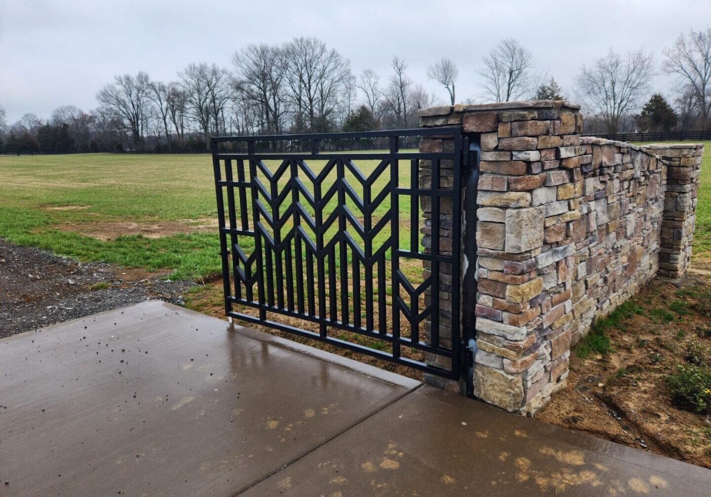 A gate that is open on the side of a stone wall.