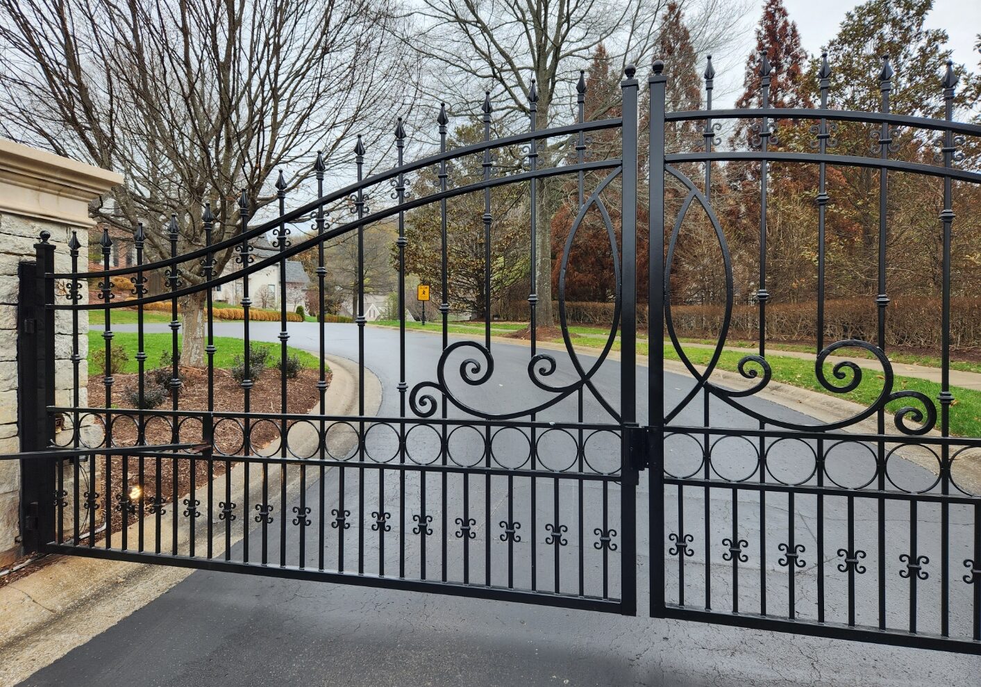 A driveway with a gate and trees in the background.