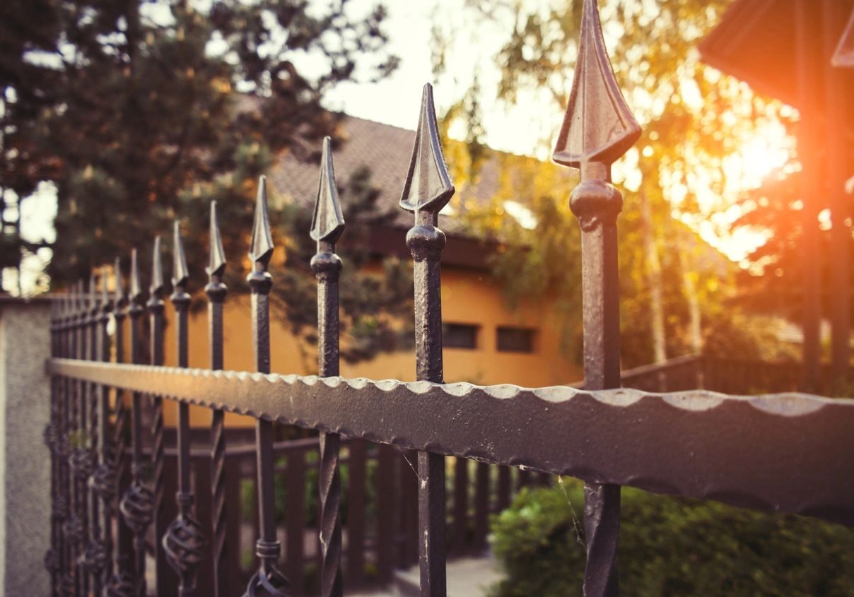 A fence with pointed top and iron bars.